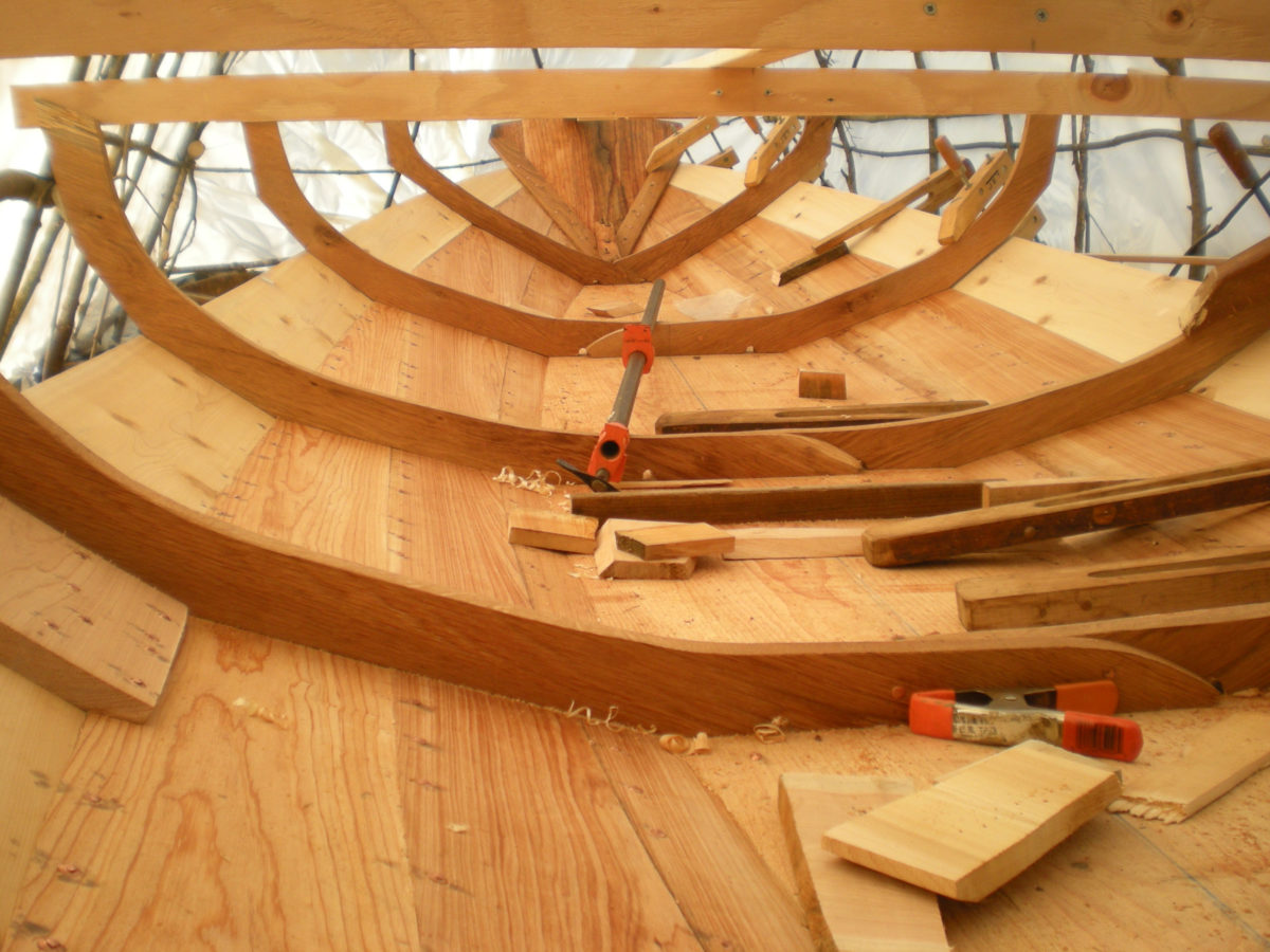 The garboards are built up of three planks joined with flush dory bevels and rivets. The seams between them are visible here with one running out at the transom and the other at the garboard's upper edge. To the far left is one of the butt blocks on the broad strake.