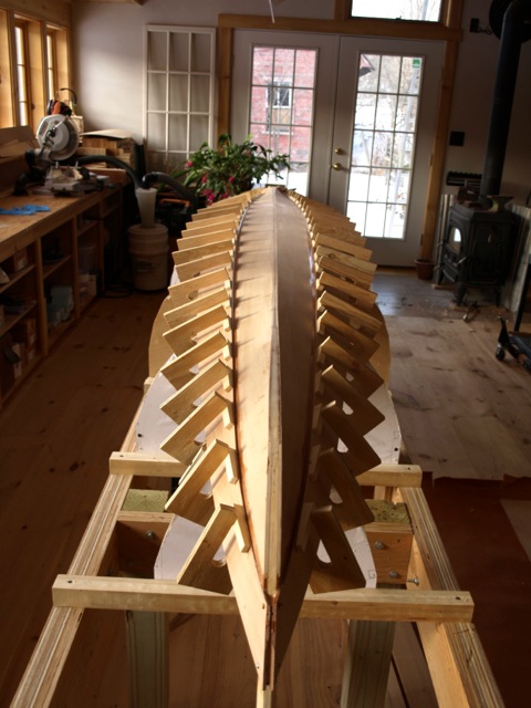 The second strake goes on with the aid of dozens of fixed plywood clamps and wedges.