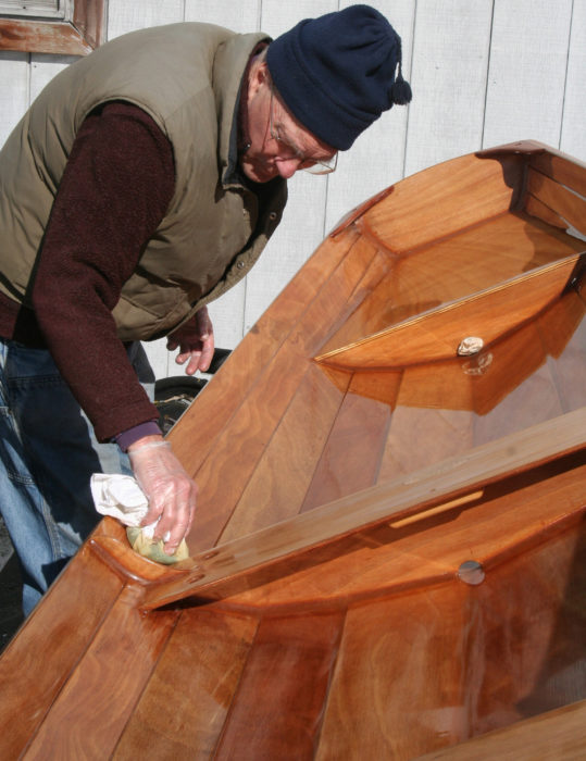 The varnish is wiped on in "panels." Here Don is applying varnish to planks bordered by the thwart frame and the transom and stern seat compartment.