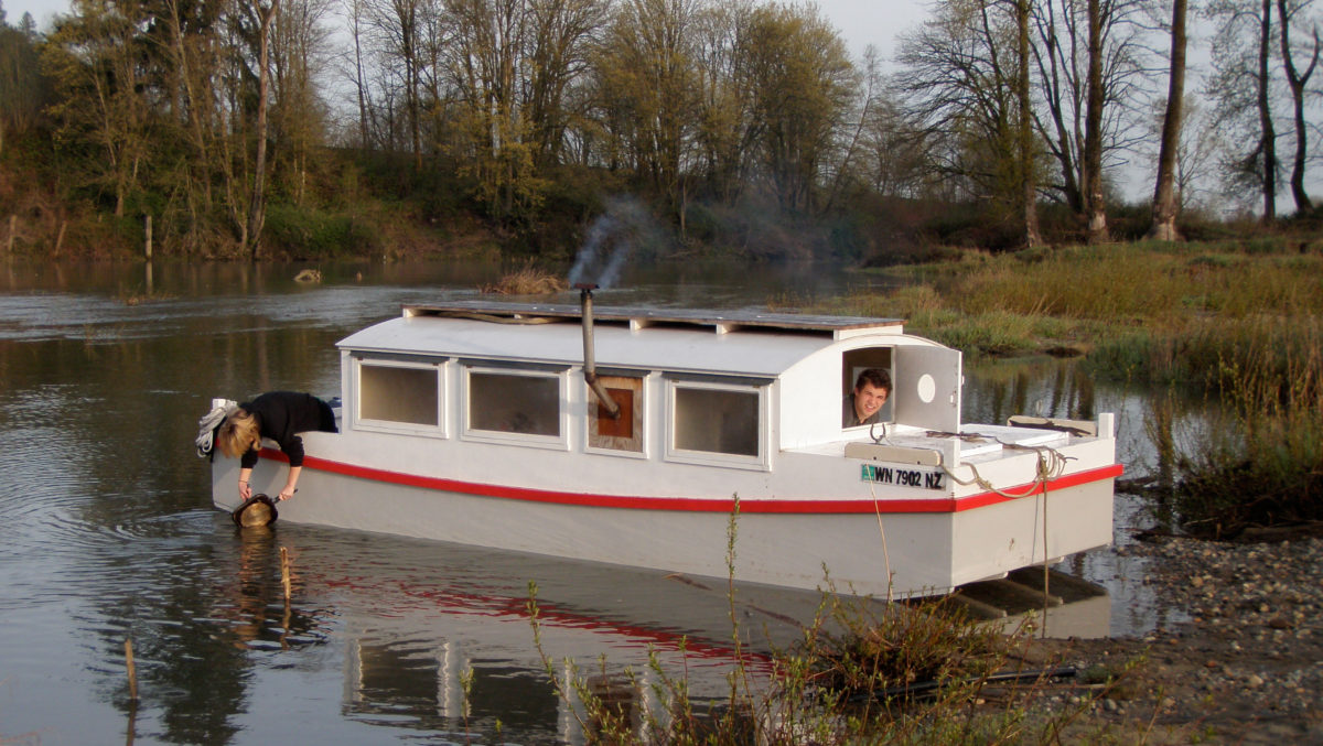 After spending a quiet and cozy night with BONZO aground on a gravel bar Alison does the dishes while Nate tidies the forward sleeping quarters. The rising tide floated BONZO for the downstream home stretch on the Snohomish River.