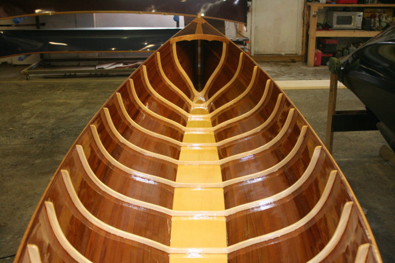The ribs start as thin but wide strips of spruce. They're steamed and clamped around a form; after they've have dried, they're removed from the form for an application of epoxy. They are clamped back on the form until the epoxy cures. Each completed piece yields five ribs in the thickness shown here.