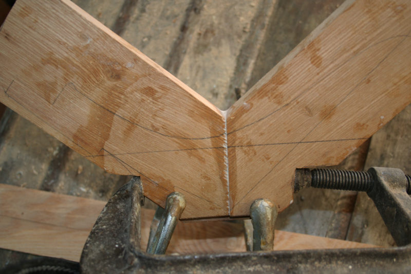 A large clamp squeezes the miter joint tight and two small clamps squeeze the wood tight tight against the spline.