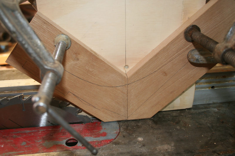 I used a shop-made tenon-cutting jig to cut the kerfs for the splines. It straddles and slides along the rip fence. Cutting off the corners of the two pieces being sawn gets rid of wood that doesn't need to be run through the saw. I have two blades stacked on the saw arbor to cut a 1/4" kerf.