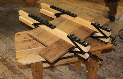 The angled arms of the system pivot to allow the clamps to accommodate work up to 6" thick as well as apply pressure to the faces of the boards being clamped.