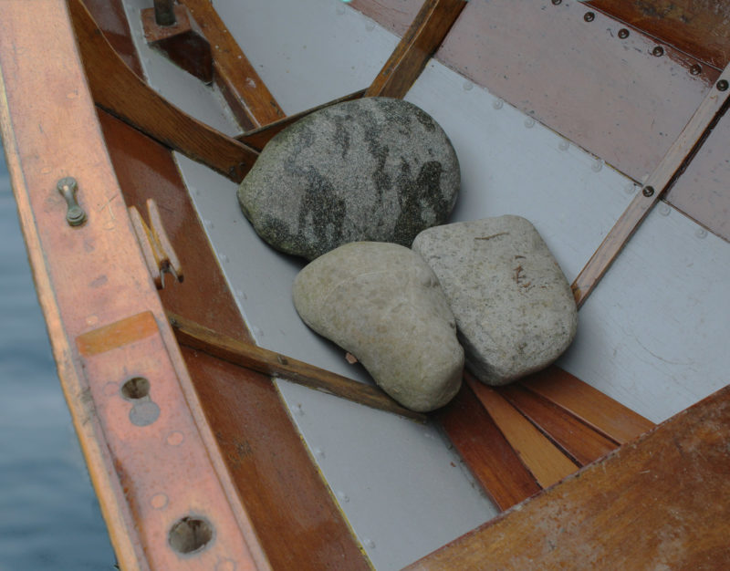 This double-ended gunning dory, like the author's Swampscott dory, has no skeg, so dory stones can settle the stern deeper in the water and improve tracking in a following sea. The three stones here together weigh about 60 pounds.