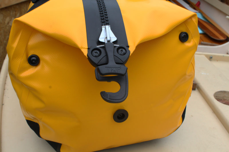 The Duffle has a cable under the zipper pull permits using a padlock to lock the zipper. The hook at the end of the zipper engages the button at the bottom of the duffel.