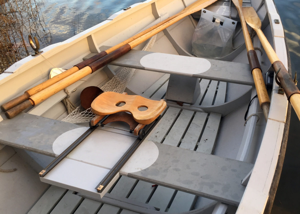 The sliding seat rig, spanning a thwart in the author's dory, has shorter tracks than those used in racing shells, but is well suited to using the same oars and locks that are used for fixed-seat rowing. Note the foot brace secured to the floorboards under the aft thwart.