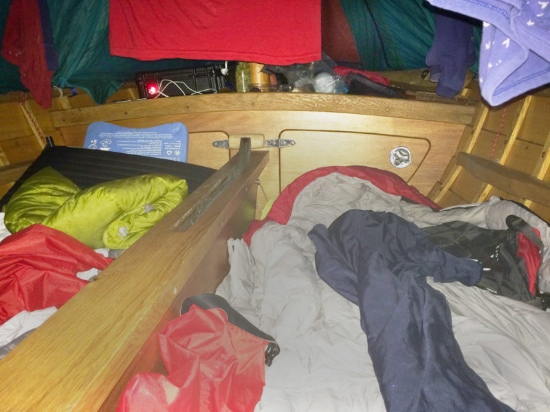 Our sleeping arrangements aboard DUNLIN under the boat tent were quite snug but we usually slept well. Mat made all of the thwarts removable so that we could take them out at night and lie either side of the centerboard. We both had inflatable sleeping pads and good sleeping bags which we stored rolled small in waterproof bags in the lockers during the day. There was no space for pillows. Clothes that got wet in the rain would hang overnight above us.