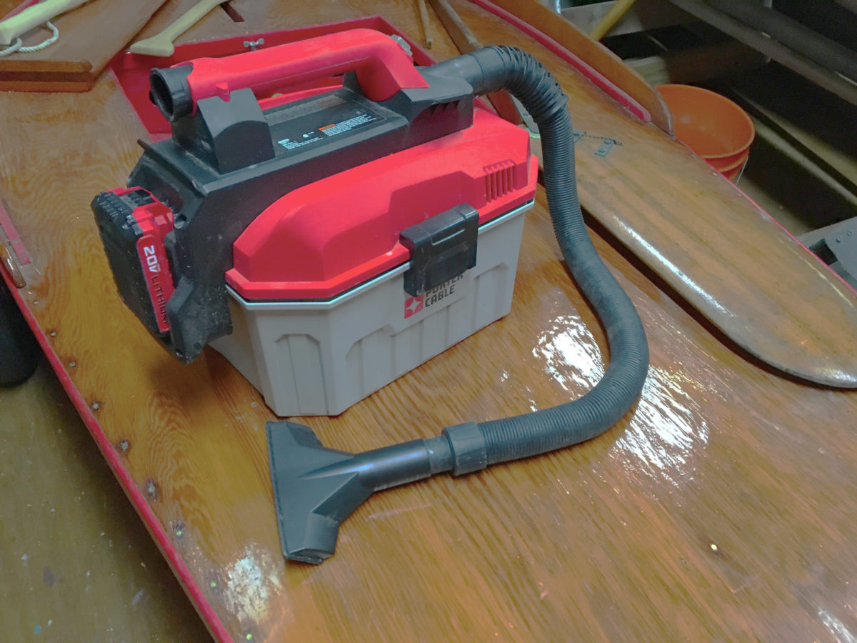 The vacuum carries a crevice nozzle in the handle and a battery on one end. When not in use, the wide nozzle clips into a recess in the other end and the hose snaps into hollows around the whole case.