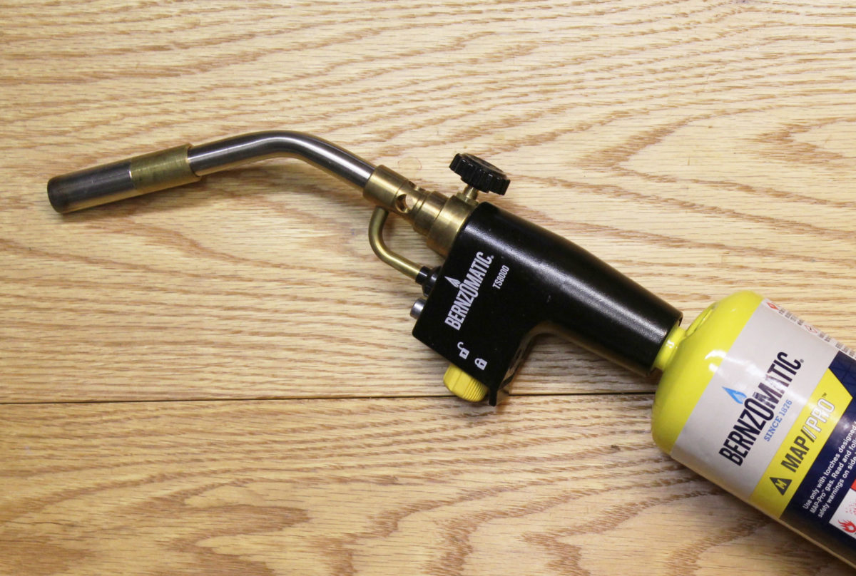 The yellow trigger turns the gas on and ignites it. The trigger can be locked in the off position by turning it clockwise and locked in the on position be depressing the silver-colored button above it. The black knob on the opposite side controls the flow rate of the fuel.