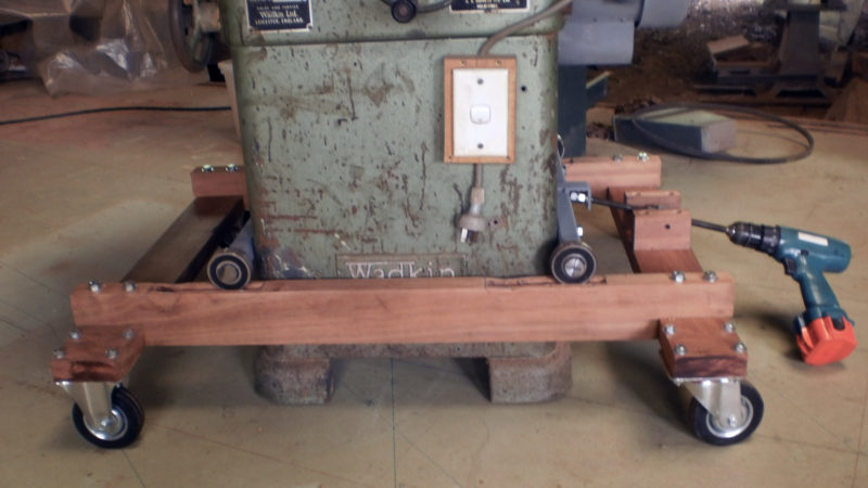 Peter developed a system for moving heavy shop machinery. This table saw is supported by four ball bearings that ride in slots on top of a wooden frame fitted with casters. a threaded rod, spun by a drill as needed, pulls the machine, and the bearings ride up the slope cut in the slots, lifting the table saw from the floor.