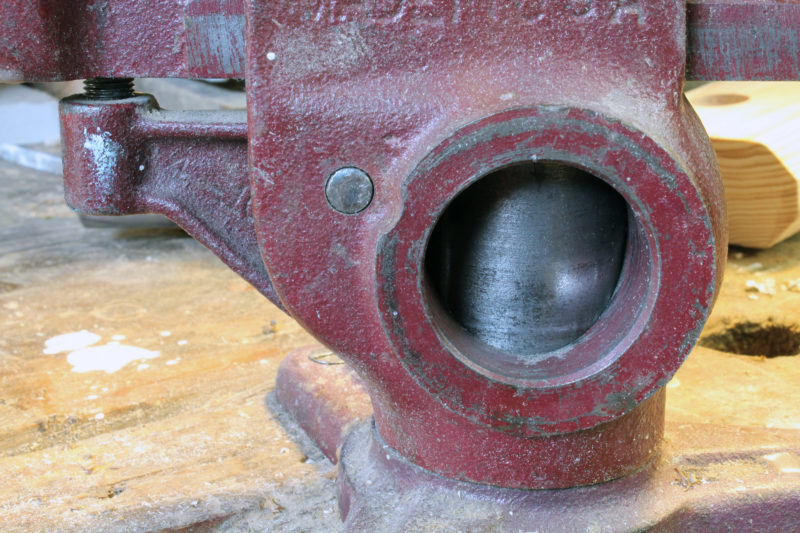 The "dog" is the little arm to the left. It pivots around the small pin, and as the vise grips something, it presses down on the dog's set screw, and then the dog presses against the base's post.