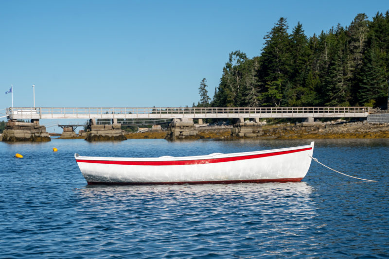 A white Catspaw Dinghy with red trim sits anchored in the water.