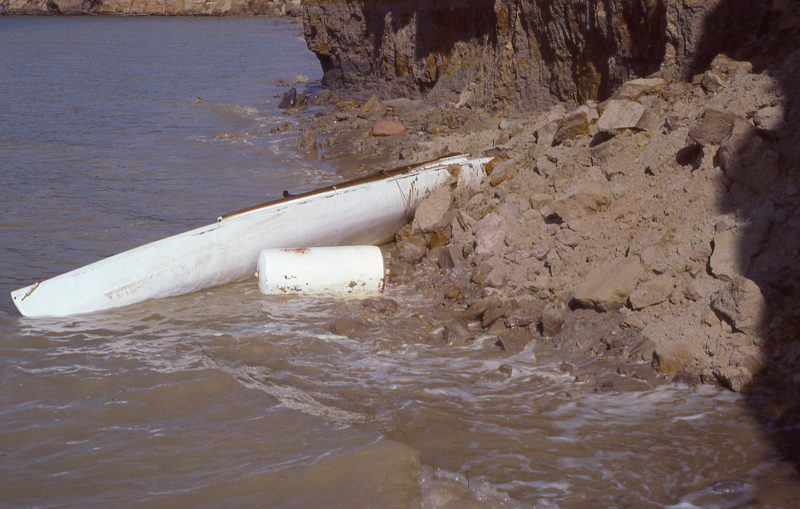 The aft-most third of the canoe is buried under a few feet of loose sand and rock.