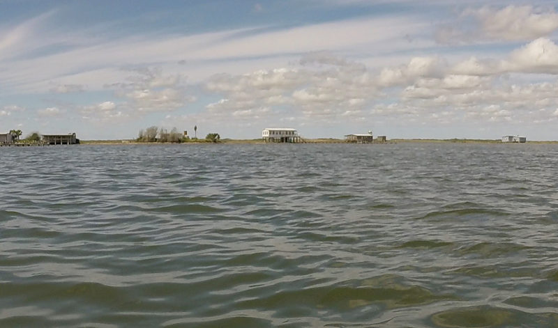 Four cabins on the shoreline seen from about a quarter-mile out on the water.