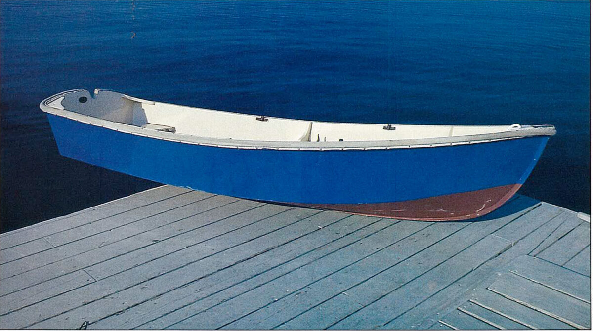 Color photo of blue rowboat sitting on a dock.