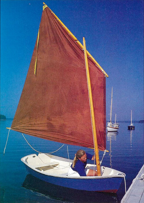 Woman installing a red sail on a blue rowboat.