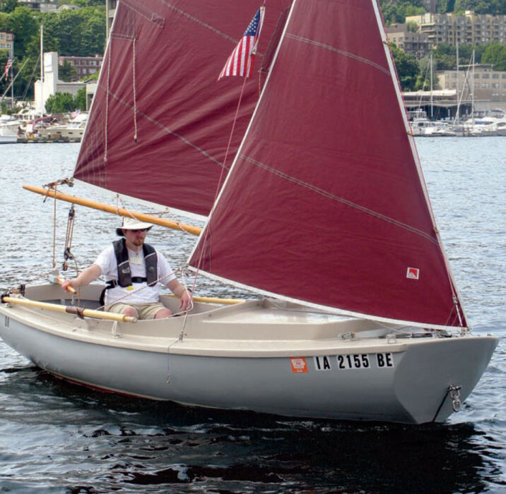 Sailor pilots the ADVENTURE camp-cruiser with maroon sails.