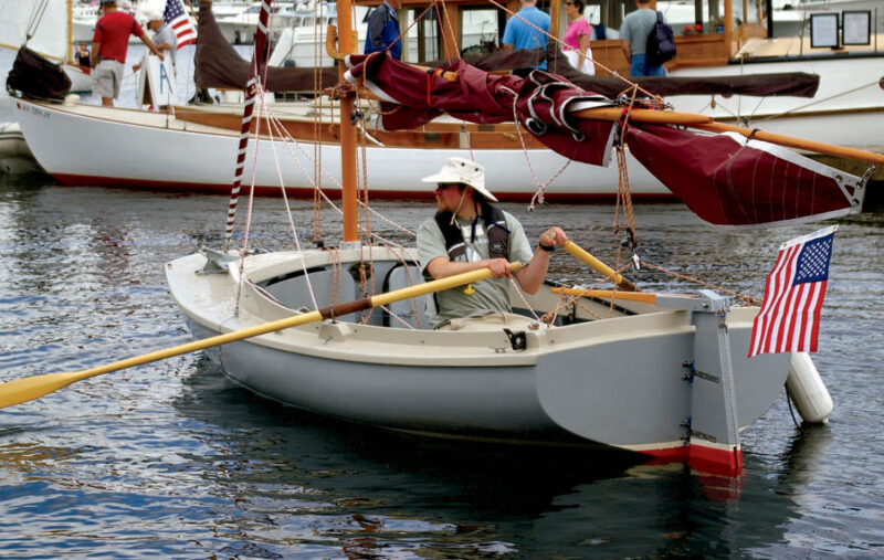 Man in white hat paddles his ADVENTURE camp-cruiser into a docking area.