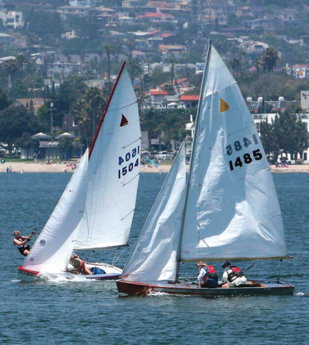 Two Geary 18 dinghies with white sails race on the water.