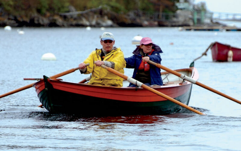 A man and woman row a Harrier double-ender boat.