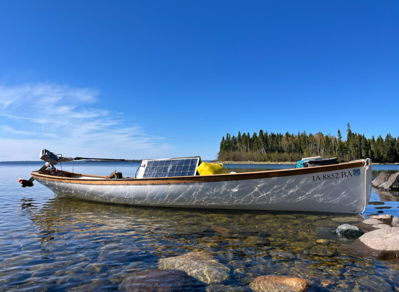 White boat equipped with outboard motor and solar panels.