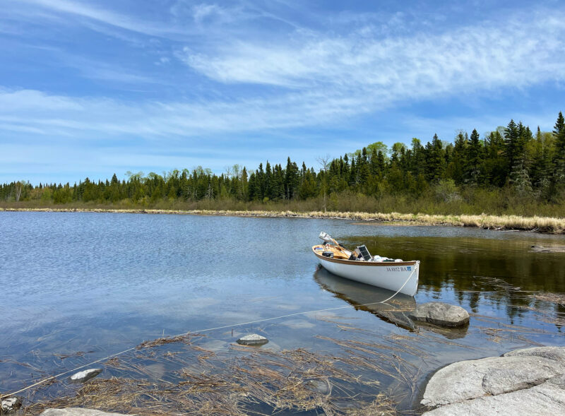 White boat sits anchored near a rocky shore near Henry's Harbour.