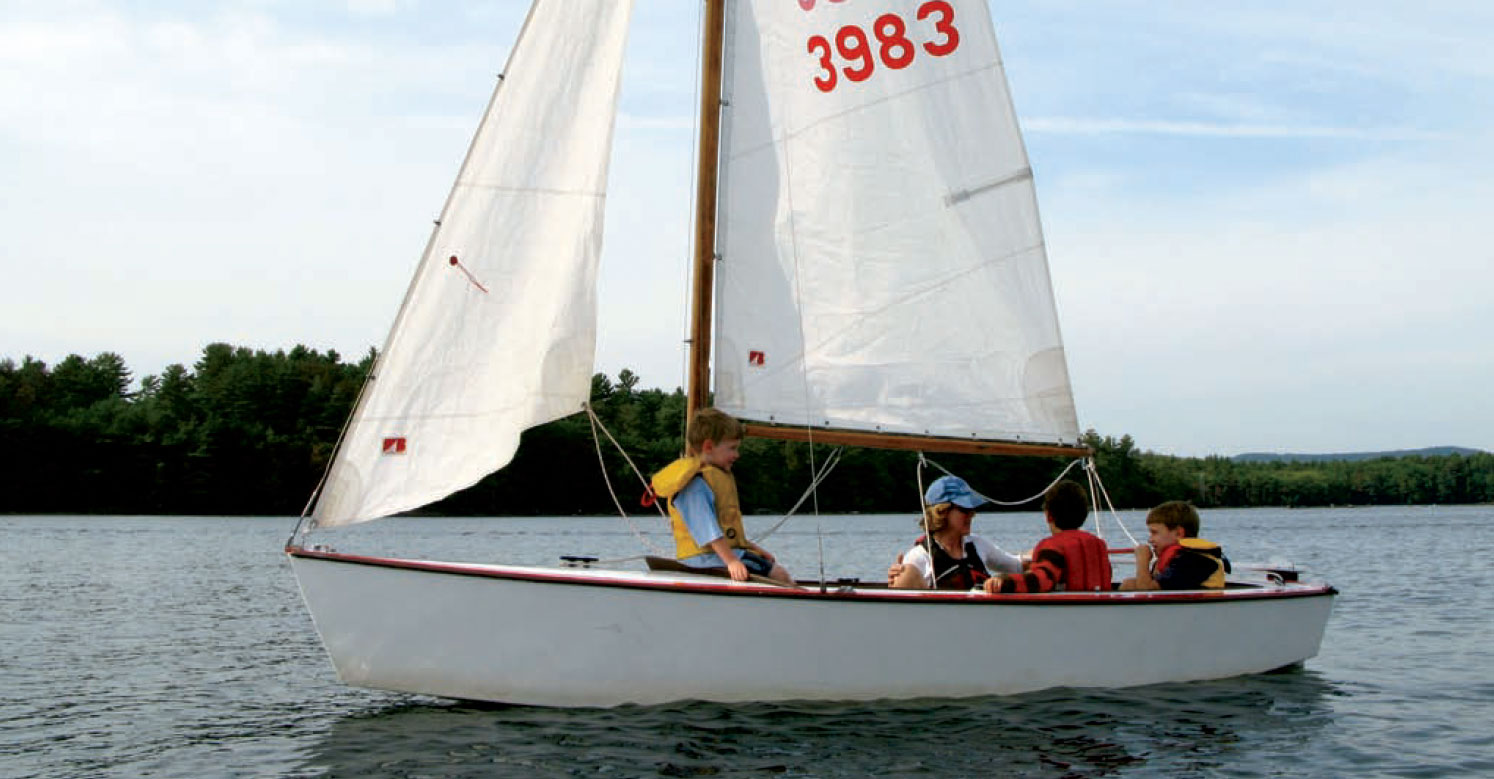 Side view of the Blue Jay-class sloop with kids and a woman aboard.