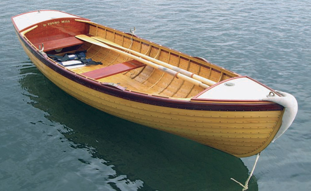 Columbia tender sits moored in the water with a pair of oars stowed inside.