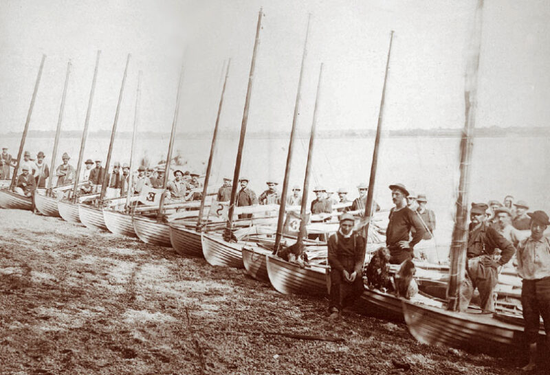 Black and white photo of several Delaware Duckers and their sailors on a beach.