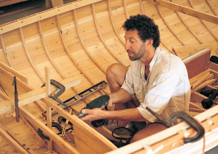 Craftsman using a power drill while building a Haven 12 1/2-footer.