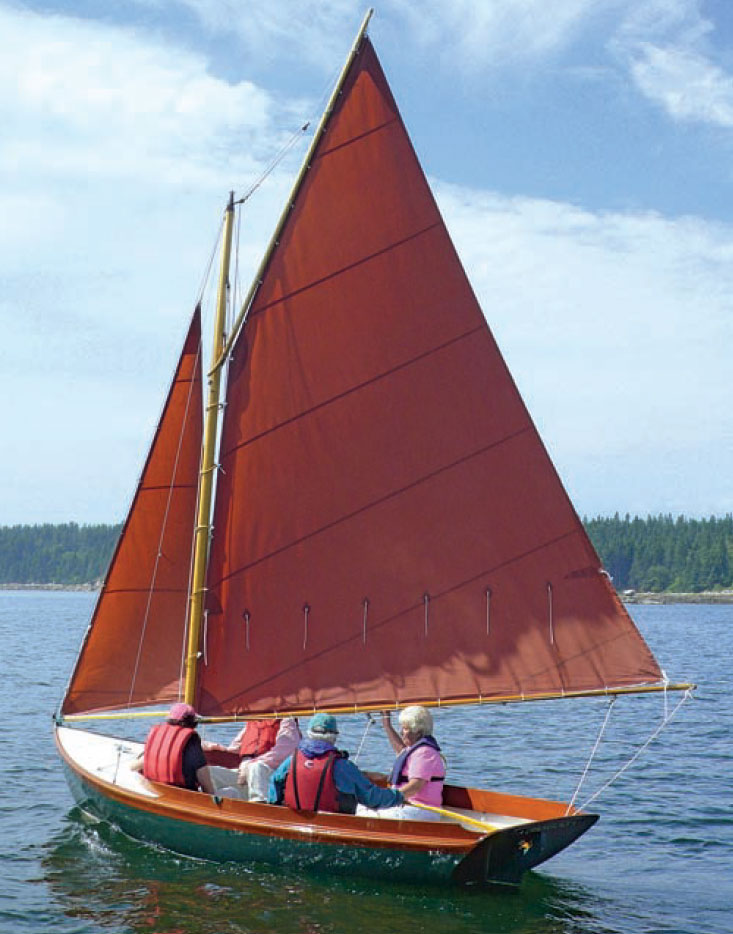 Four sailors aboard a Haven 12 1/2-footer with orange sails.