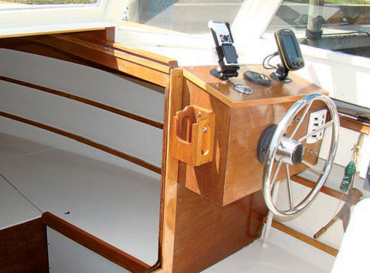 Powerboat cockpit with chrome steering wheel and navigational devices.