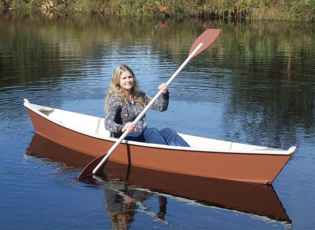 Woman sits in NEWT canoe with double paddle.