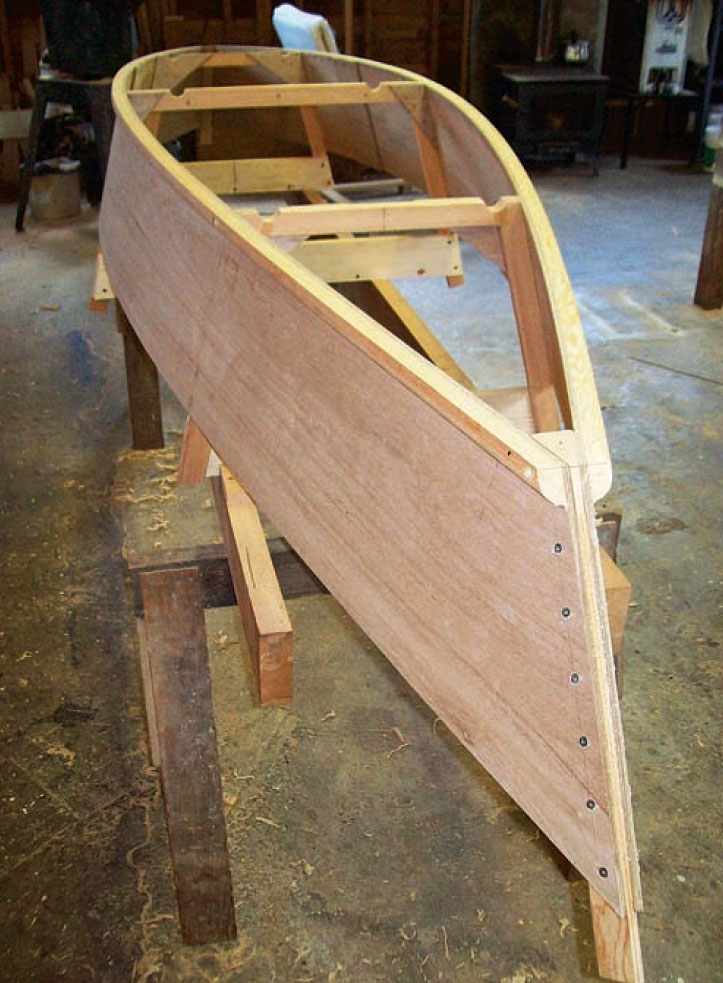 Partially built plywood canoe sits on sawhorses in a shop.