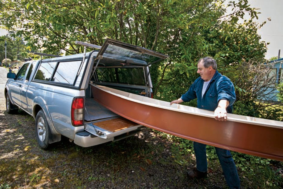 Man loads NEWT canoe into the back of a truck.