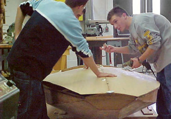 Boatbuilders working on the hull of an International Fireball.