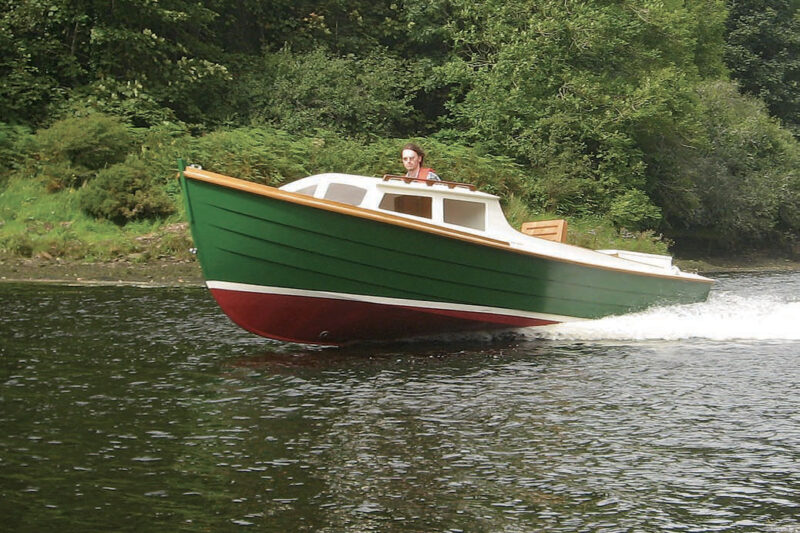 Man pilots a green Ninigret powerboat on the water.