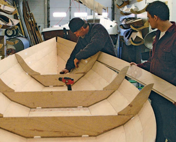 Boatbuilders work on a Northeaster Dory in the shop.