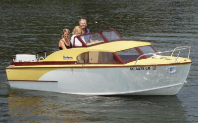 Man and two women ride aboard a yellow and white Sea Knight powerboat.