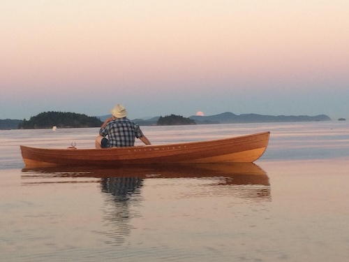 man sitting in a delaware ducker boat at sunset