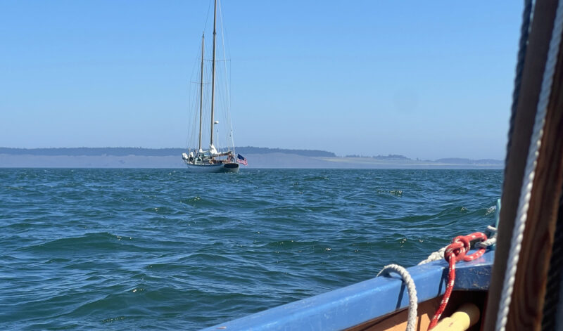 Bare-poled schooner seen over gunwale of dory