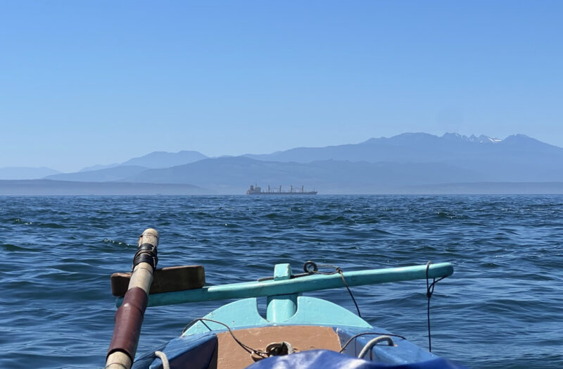 Commercial freighter seen over stern of painted dory