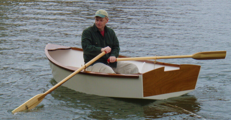 Man rowing white-painted and varnish-trimmed Guppy-9
