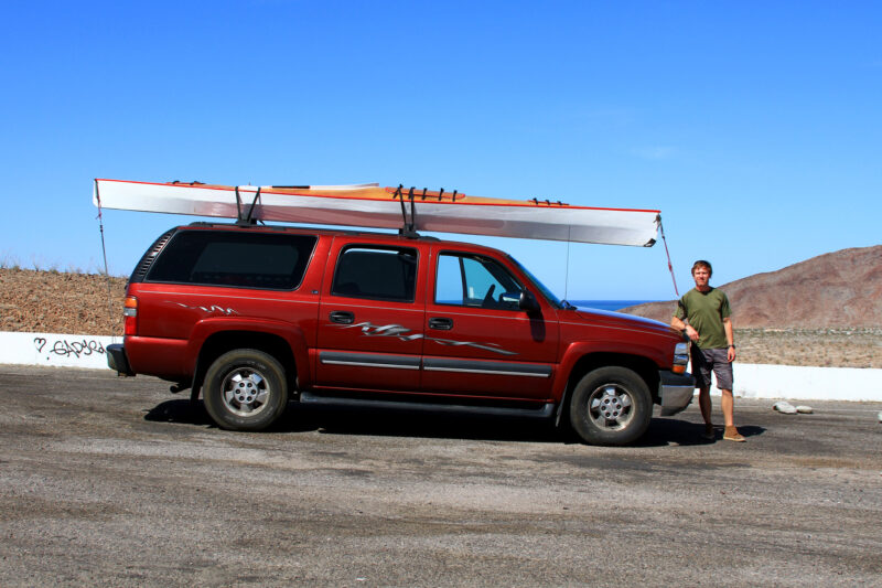 Man leaning on car with Angus Expedition rowboat on roof