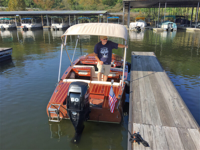 Classic runabout with canvas bimini alongside dock