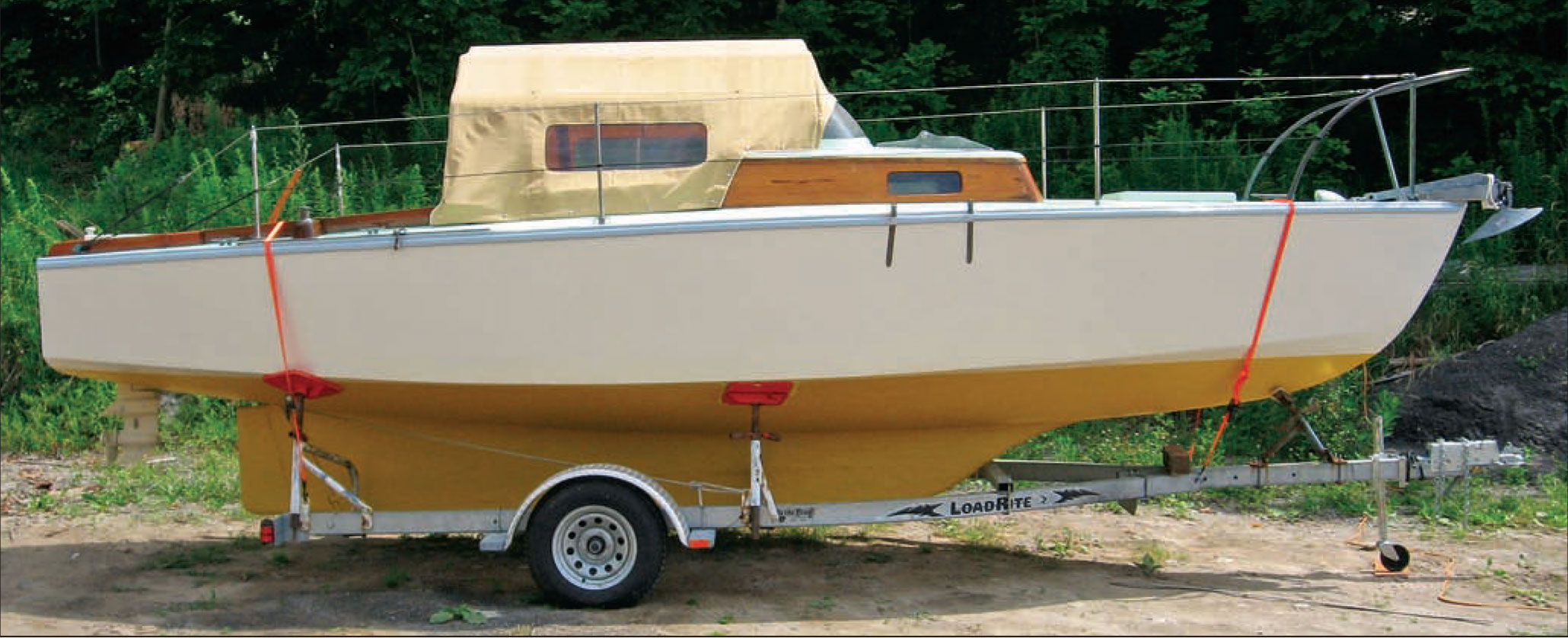 Boat with a canvas shelter set on a boat trailer.