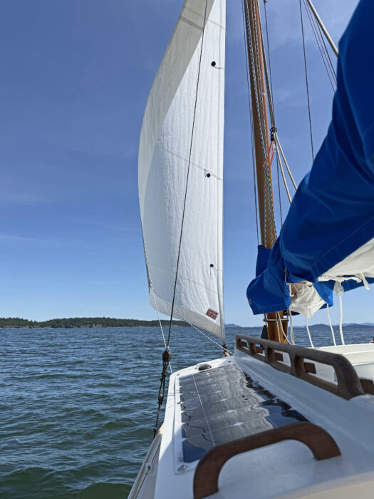 Sailboat under jib with solar panels on side deck.