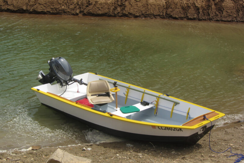 Small open boat with transom bow and outboard on beach.