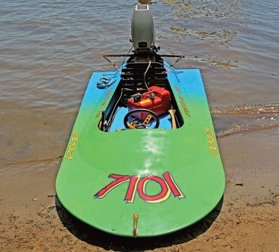 Blue and green Minimax sits ashore a sandy beach.